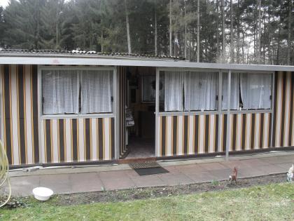 Sonniger Campingplatz mit Wohnwagen und Vorzelt.